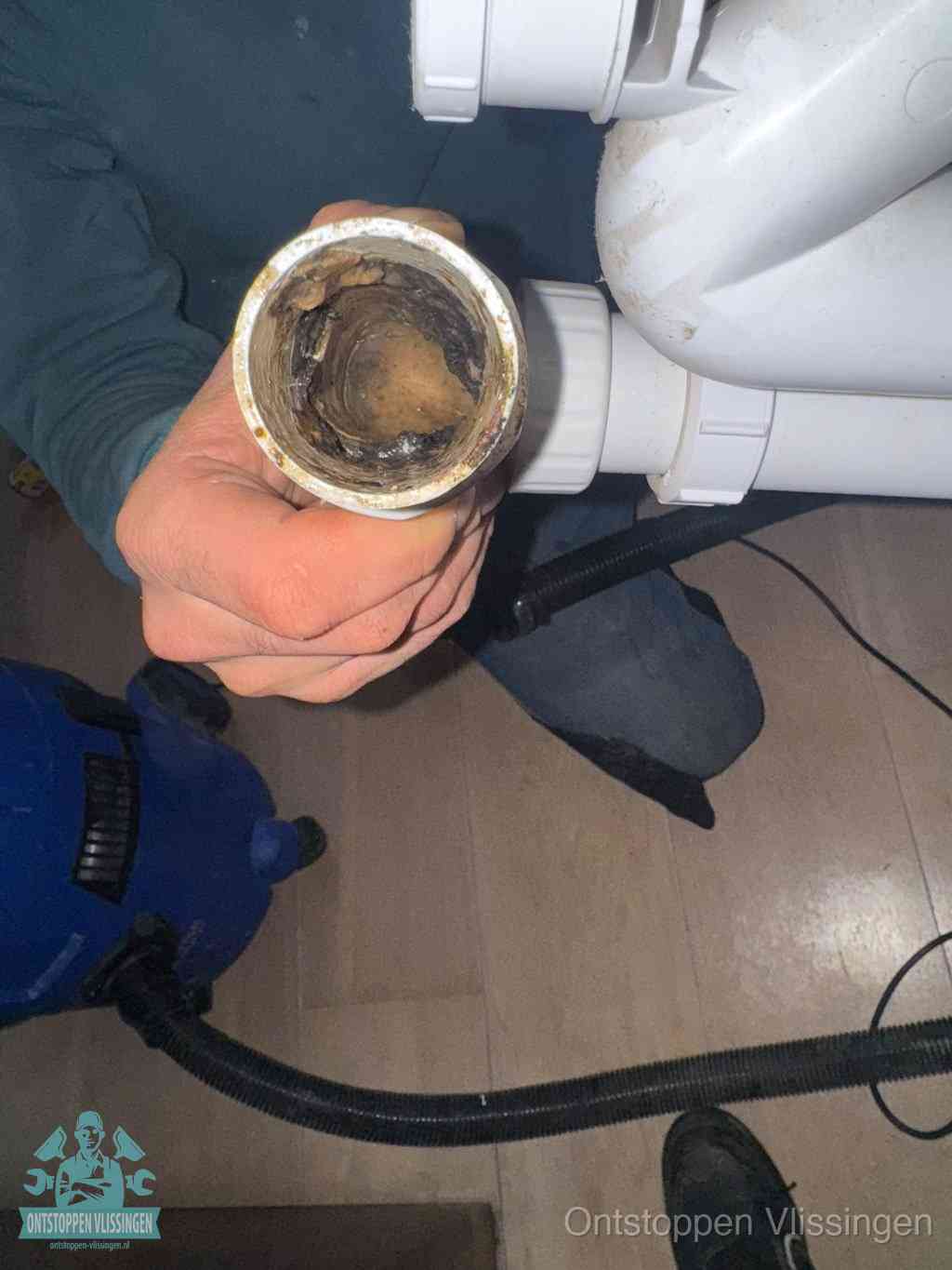 Een losgekoppelde afvoerbuis die van binnen volledig is dichtgeslibd met vet en aanslag, de meest voorkomende oorzaak van een verstopte gootsteen in Vlissingen
