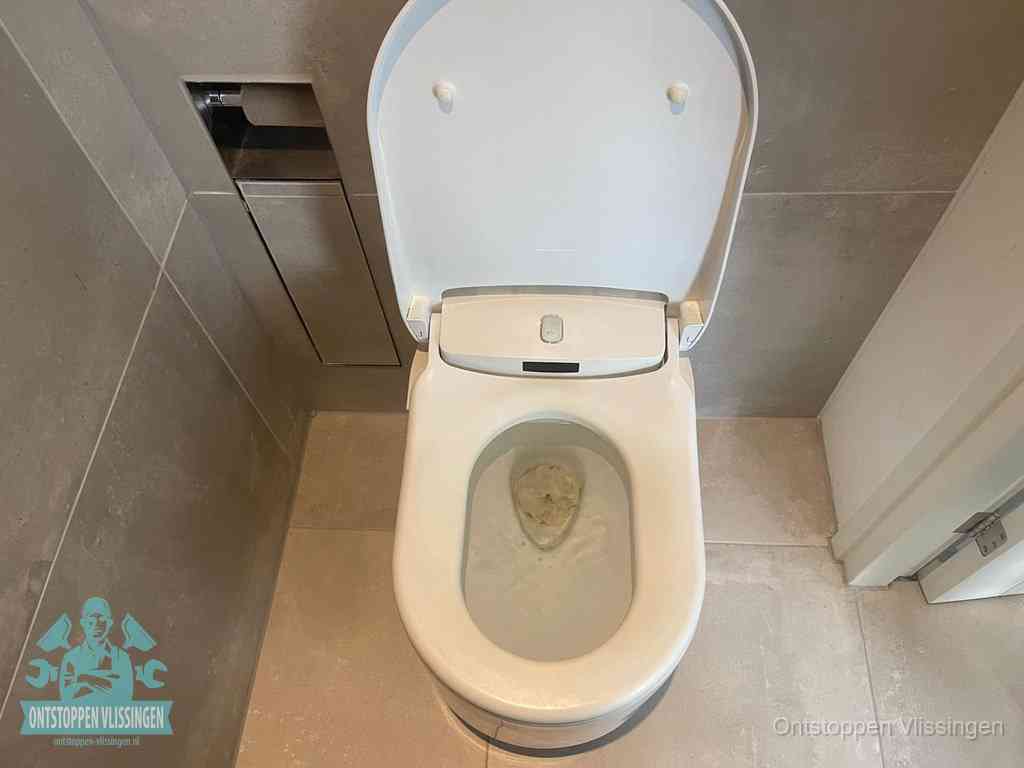 Een wit hangtoilet waarin een prop wc-papier op het water blijft drijven, een duidelijk signaal van een verstopte wc in Vlissingen