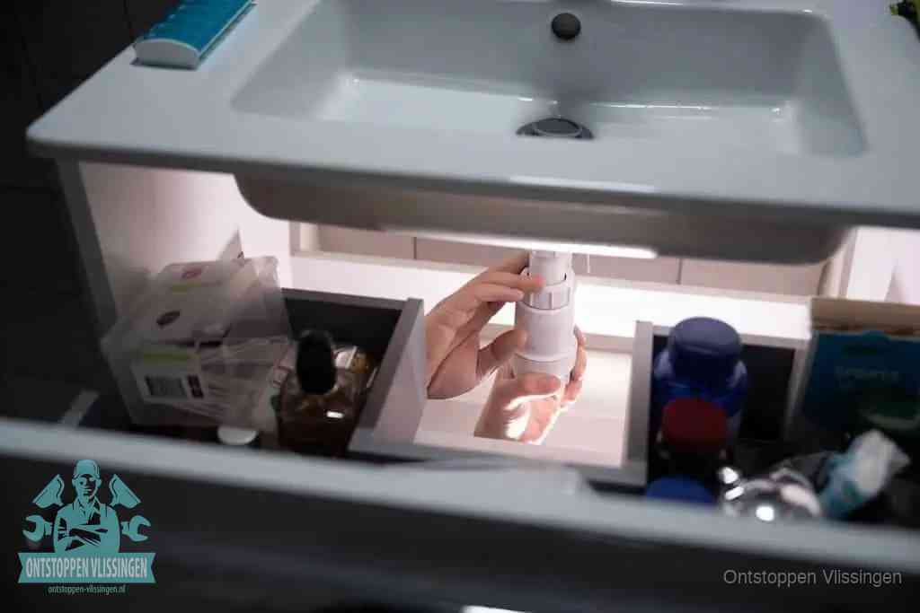 Een pompfles met zeep boven een wastafel in de toiletruimte, de warm water en afwasmiddel-methode om de wc te ontstoppen in Vlissingen